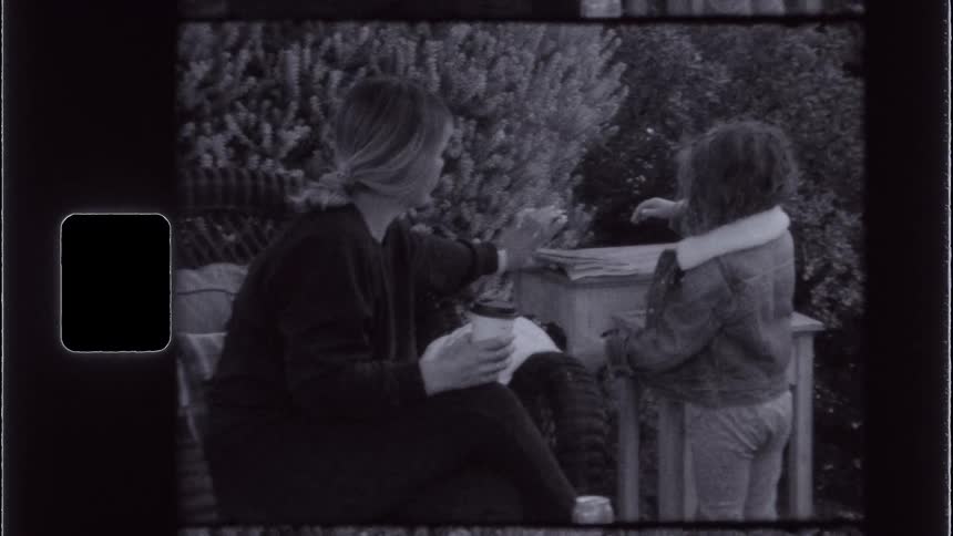 A mother helps her daughter with some books on a table