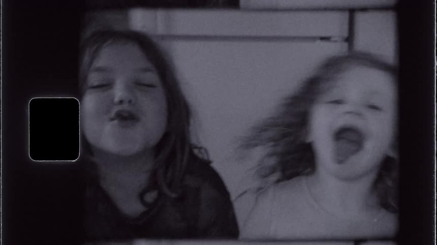 Two young sisters are sitting and goofing off making silly faces