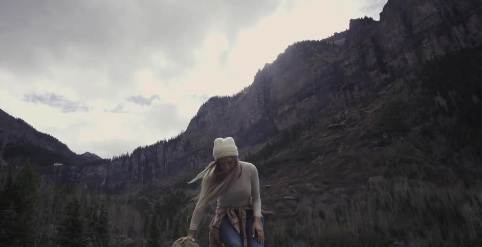 Woman climbing down a rock next to a lake