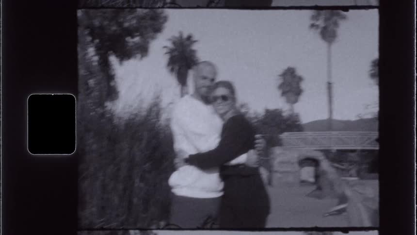 Couple stands and hugs on a path leading to a bridge during the daytime