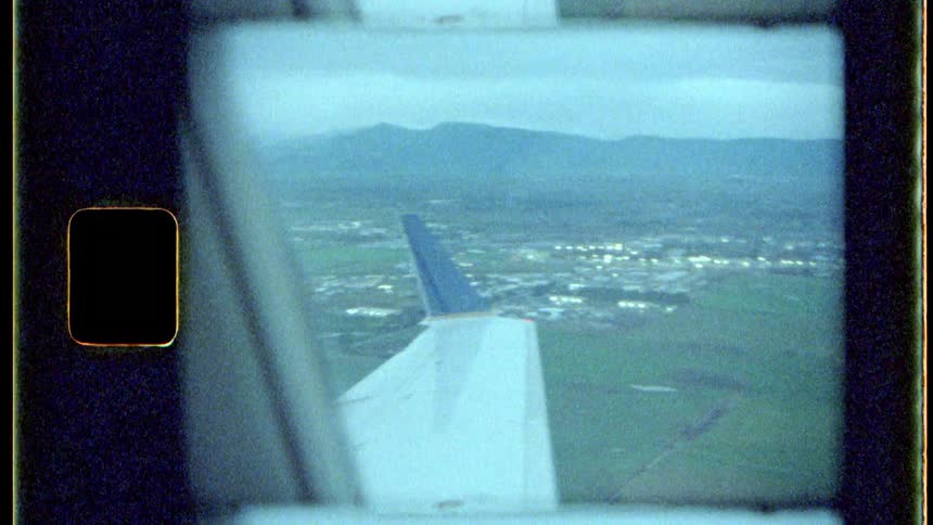 City in the background is seen through the window of an airplane in flight