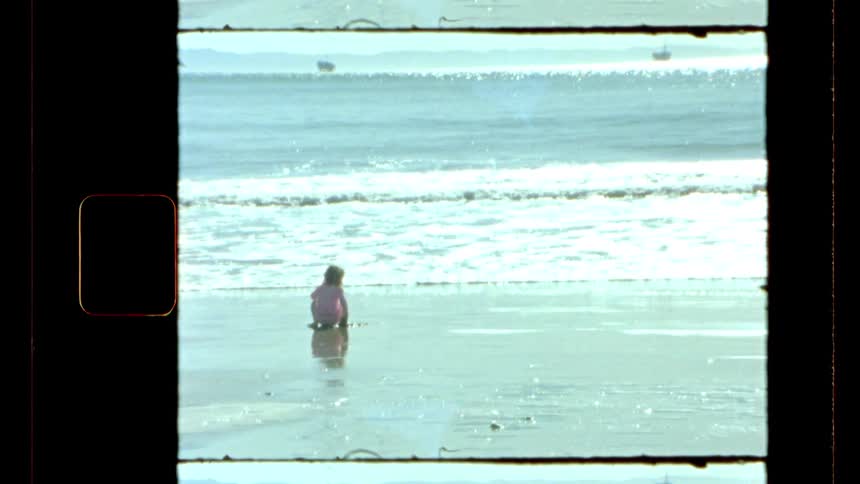 A little girl playing with wet sand on the coast of a beach