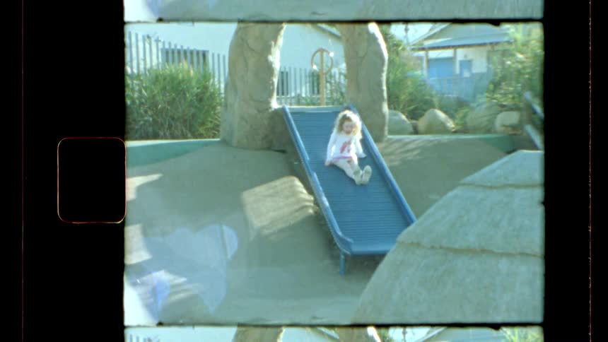 A little girl slides down a slide in a playground