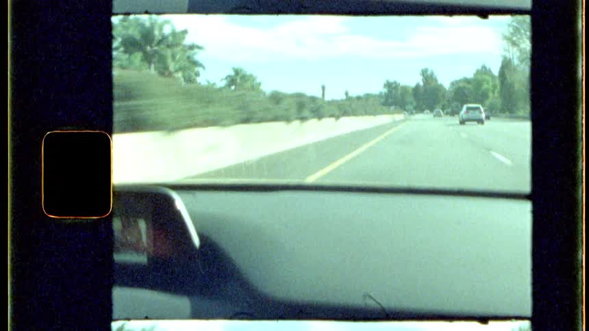 A vintagestyle shot shows a cars dashboard and windshield as the vehicle drives along a highway stretching into the distance with another car visible ahead under a bright sky