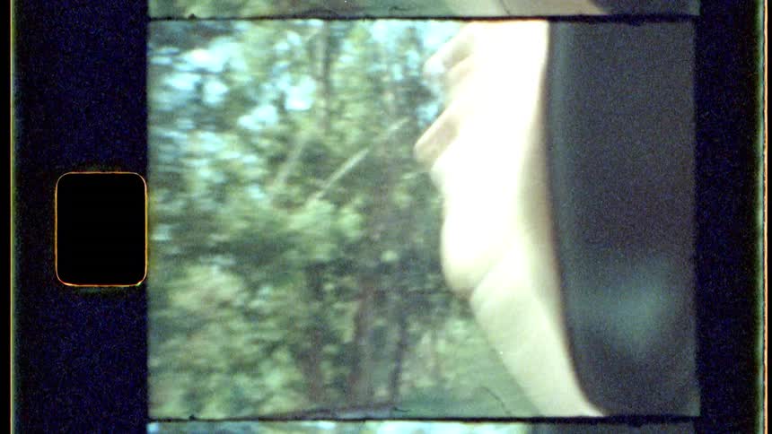 Person makes a waving motion while traveling through the woods in a vehicle during the daytime
