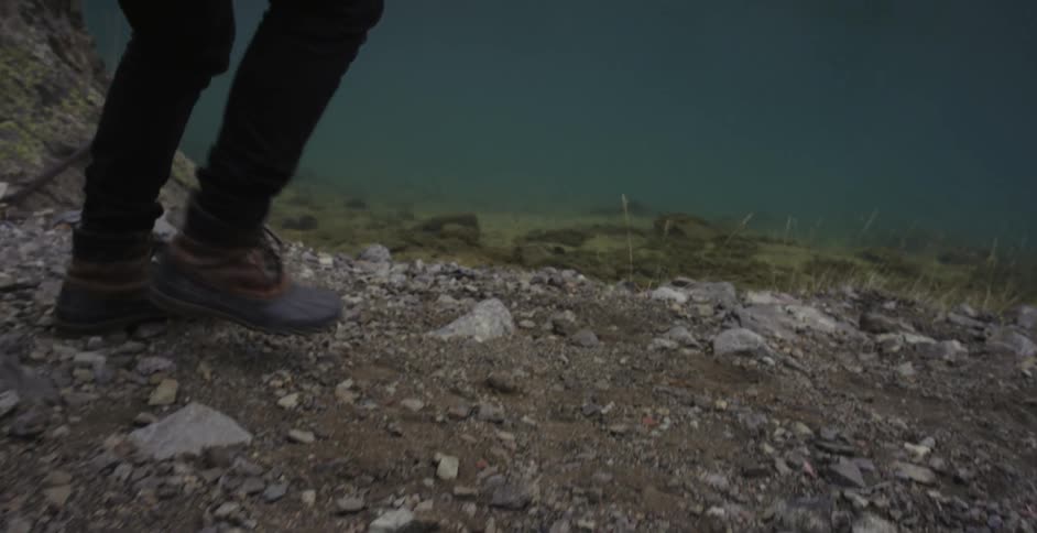 A person walking down a rocky slope to a body of water