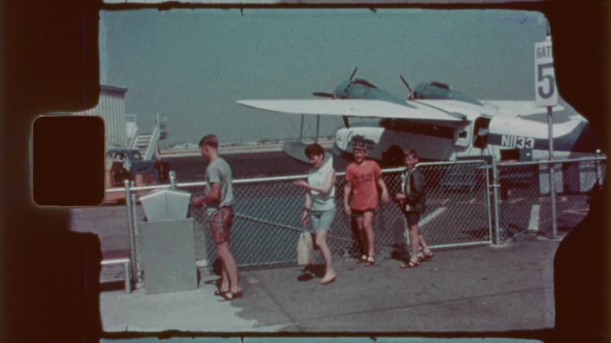 A family are looking at a plane behind the fence