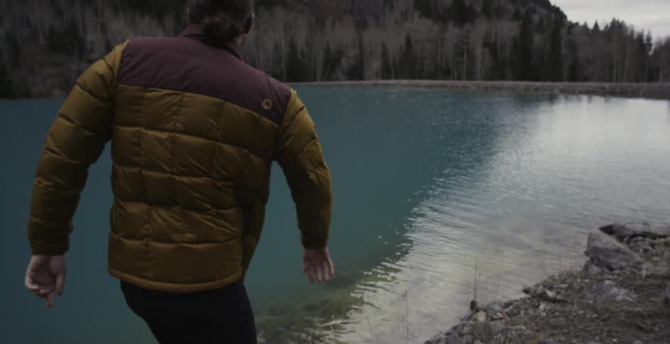 A man throwing rocks across some water and skipping them