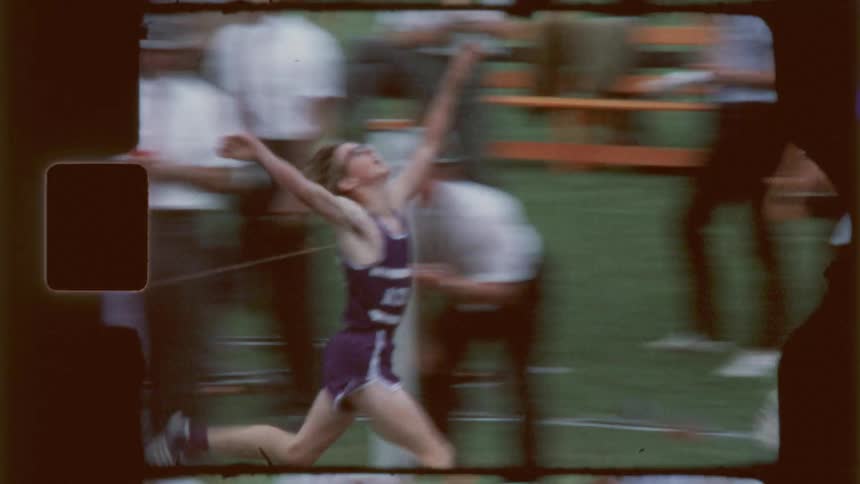 A teenage boy runs a race and hugs a teammate as he crosses the finish line on a track