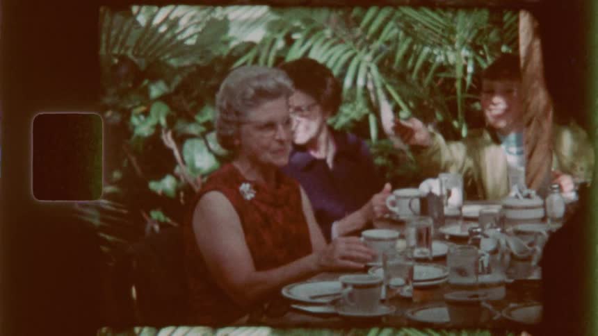 A group of people are eating outside at a large table