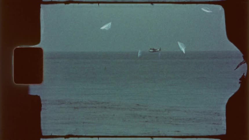 A sailboat moves through the water without its sail unfurled near other ships