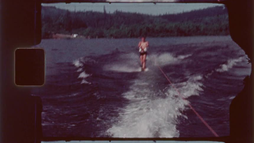 A man is surfing while being pulled behind the boat