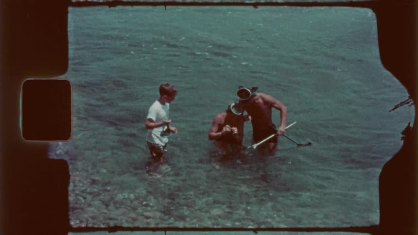 Three boys with snorkeling equipment find a sea animal and wave it around
