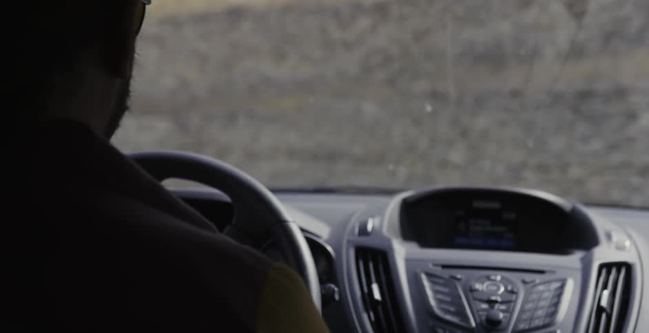 A man drives a vehicle near a rock wall
