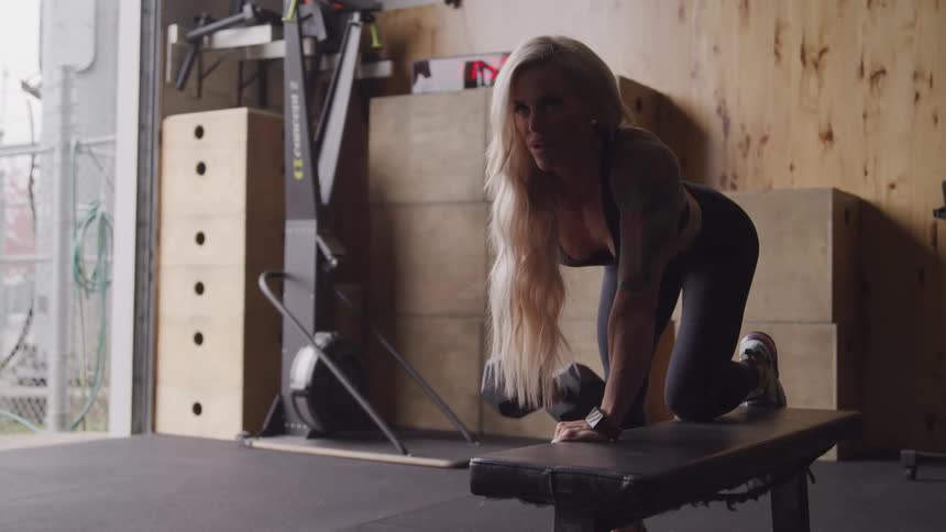 A woman is lifting a barbell in the gym