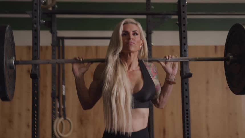 Blonde woman in a gym doing barbell squats