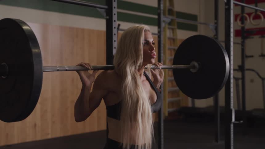 A woman is lifting weights in a gym