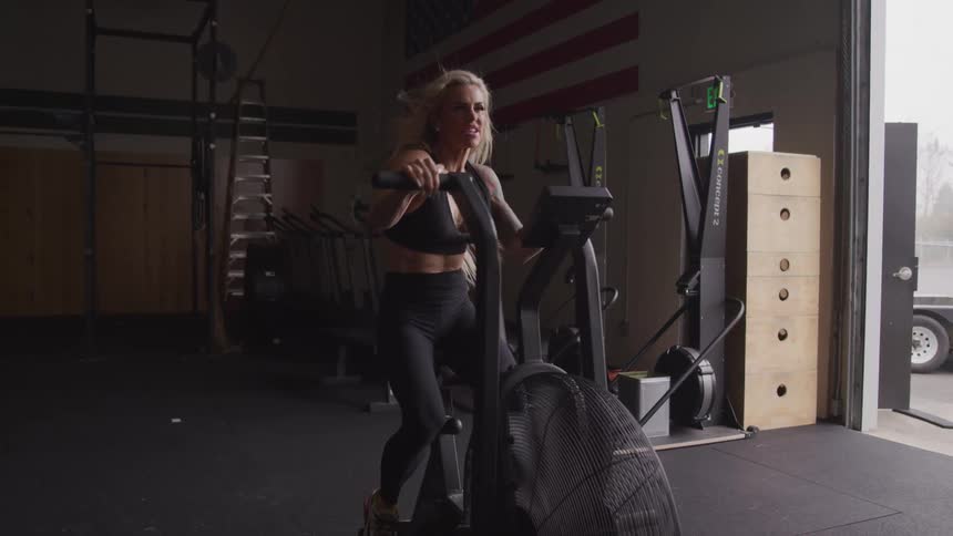 Woman is exercising on a bike in an indoor gym
