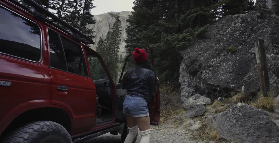 Woman in red hat jumping out of red vehicle