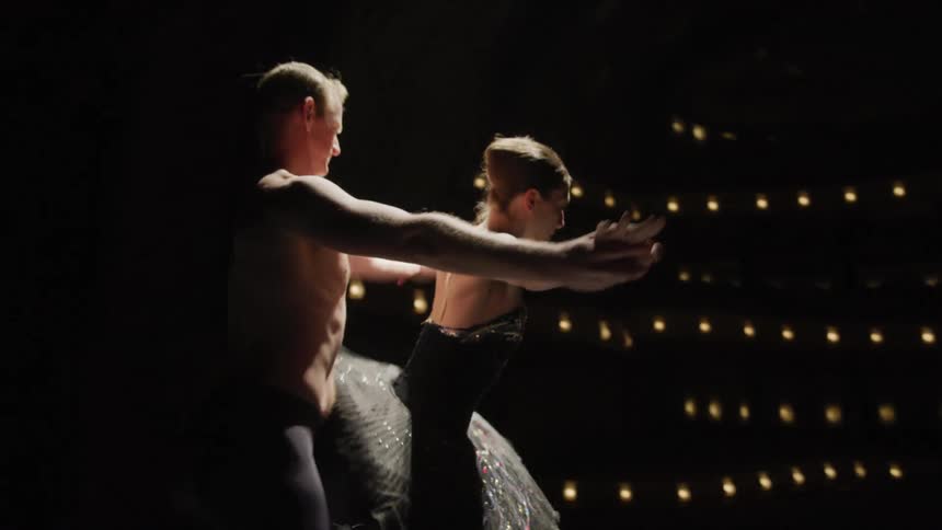 A woman lifts her leg as she dances ballet with a man