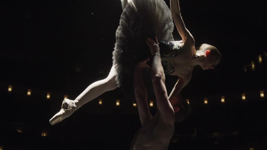 Man lifting a woman in a dance performance in an auditorium