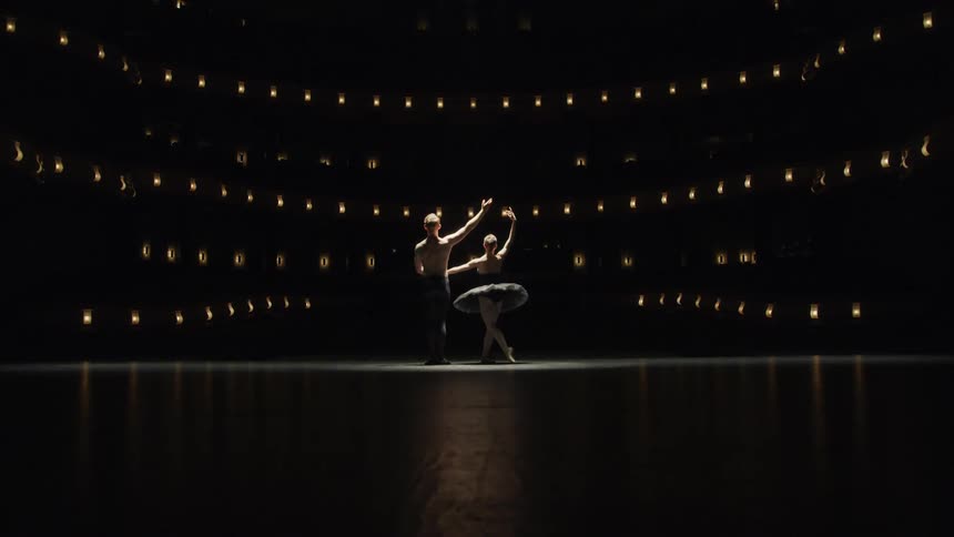 Male and female ballet dancers move together on a stage