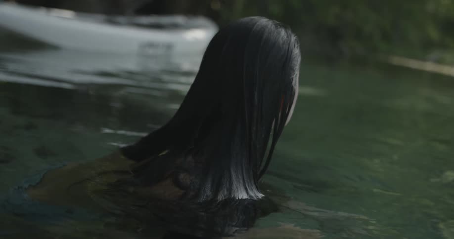 A woman resting in a lake or pond and looking around