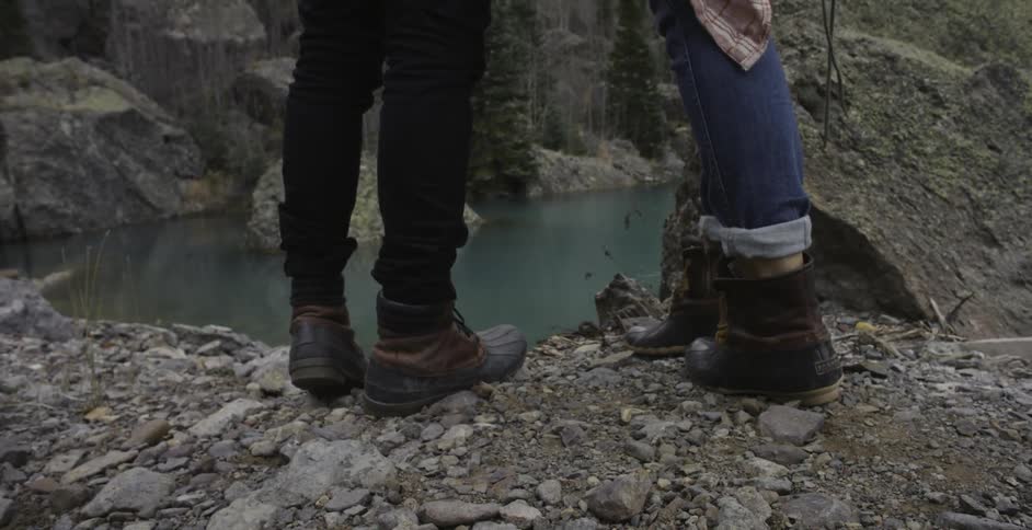 Two hikers stand overlooking a lake in the mountains