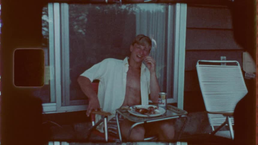 Man sitting on the porch talking happily and with a plate of food in front of him