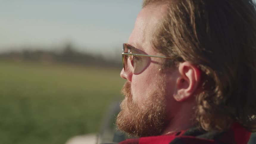 Side portrait of a man with sunglasses and beard in a natural outdoor setting