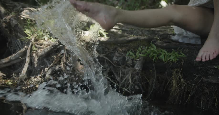 A close up view of roots and trees along a river or canal and someone kicking water