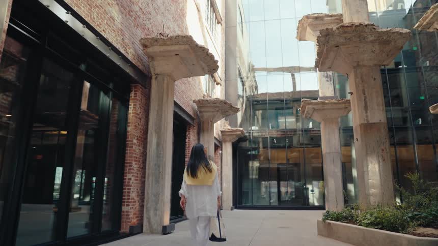 Woman walking in a modern industrial space with concrete pillars and glass walls and exposed brick
