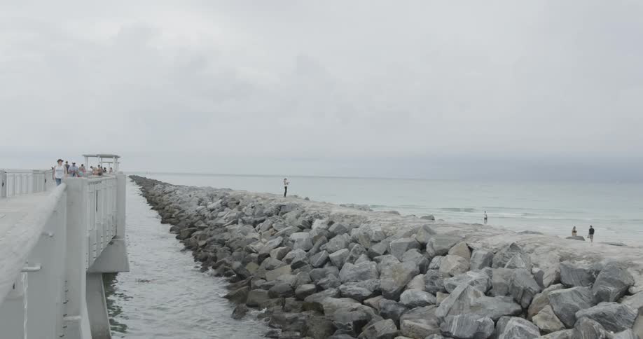 People walk on a pier on a cloudy day