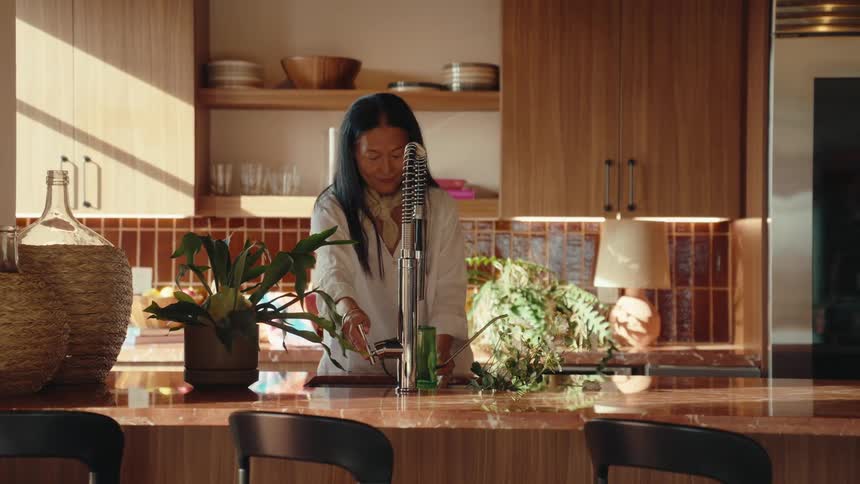 Woman in the kitchen filling a jug with water
