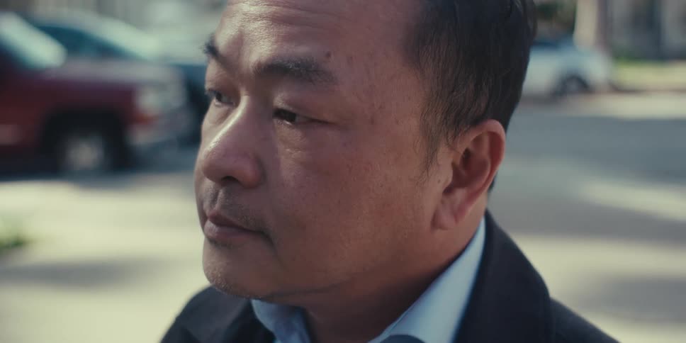 Man in blazer outdoors and looking thoughtful