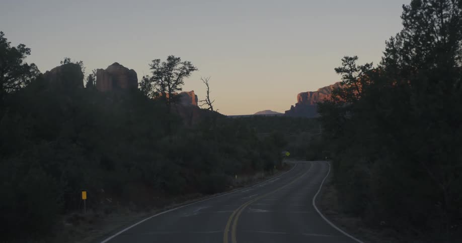 A road winding through trees with cliffs in the background