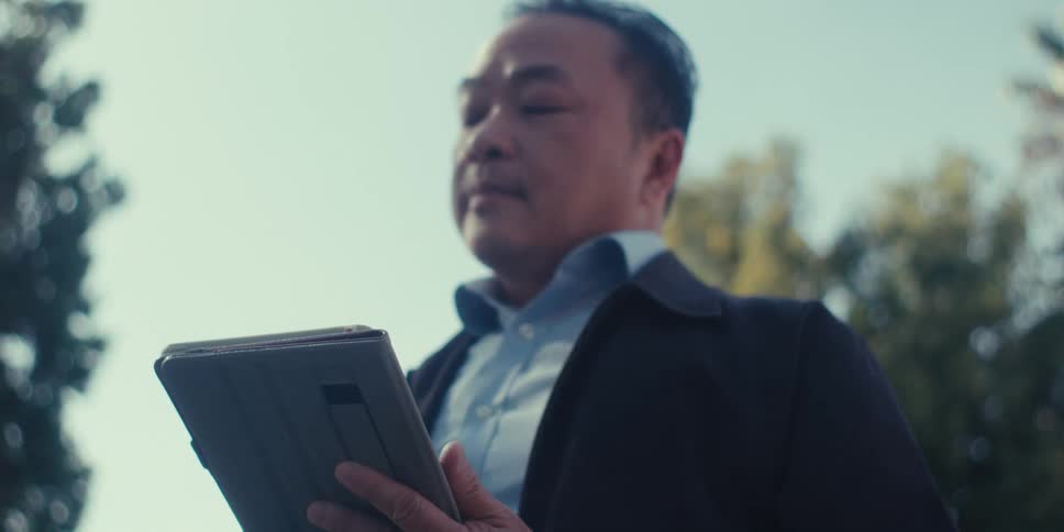 Man in blazer outdoors interacting with a tablet