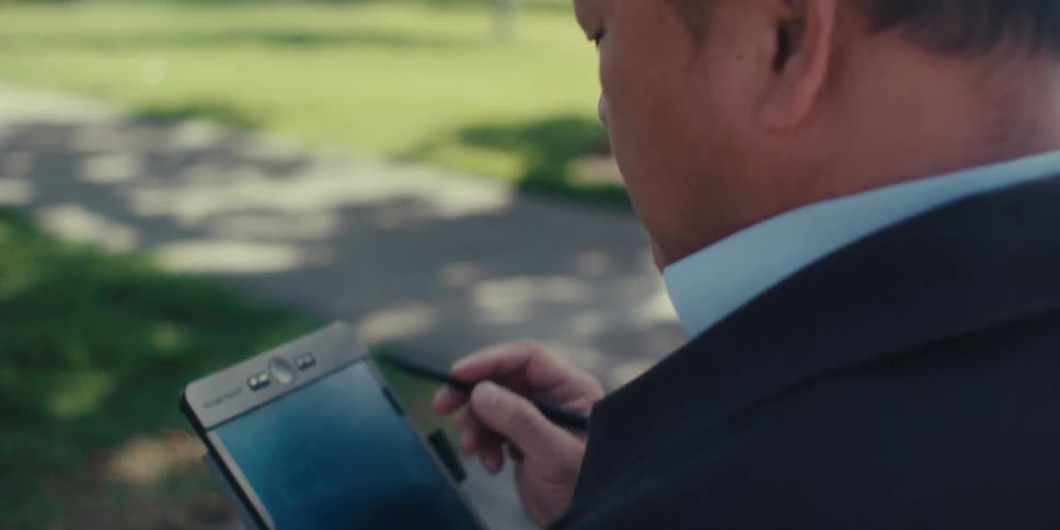 A man is writing on his tablet outside