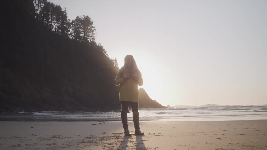 Woman in jacket on a beach at dawn