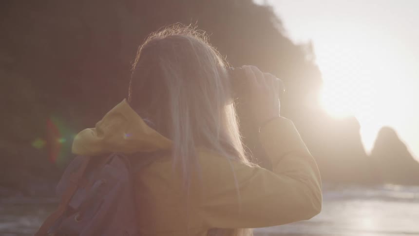 A woman is using binoculars to view the ocean