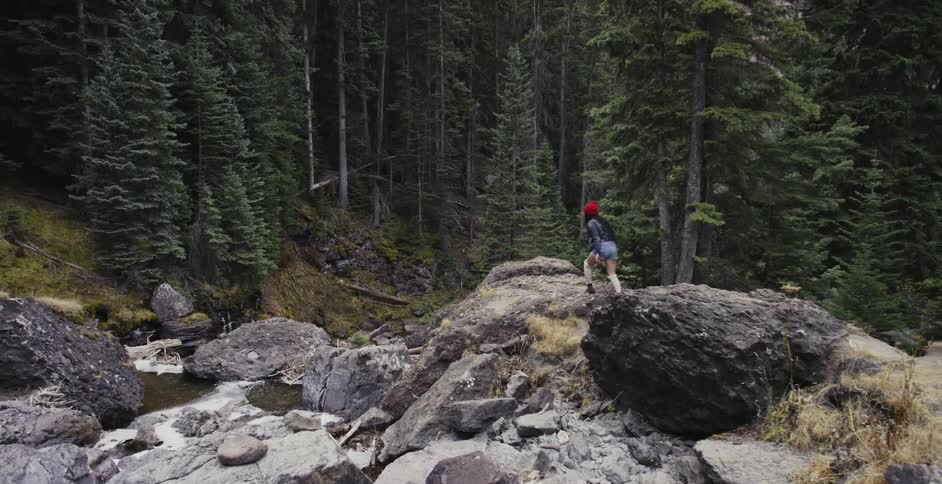 Woman hiking on large rocks in forest