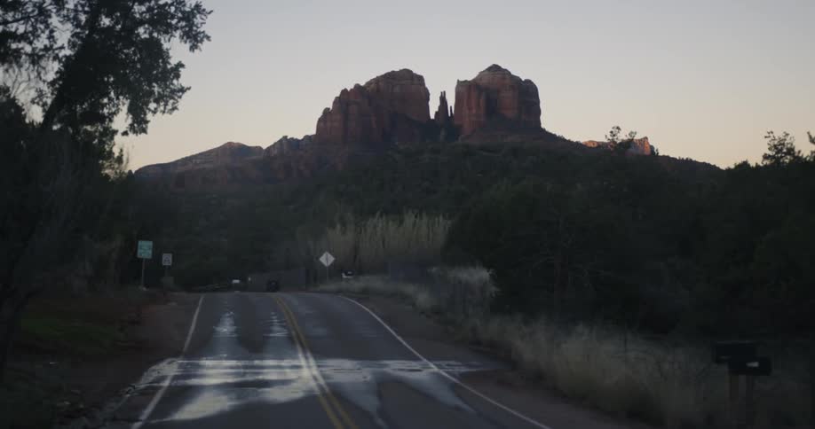A view of someone driving down a road with mountains in the background