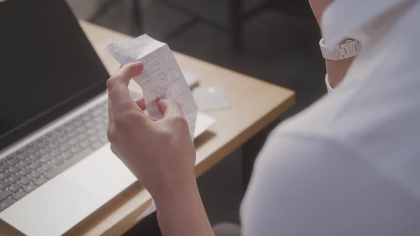 Hand of a seated person holding a receipt