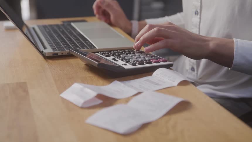 A man is using a calculator near his computer