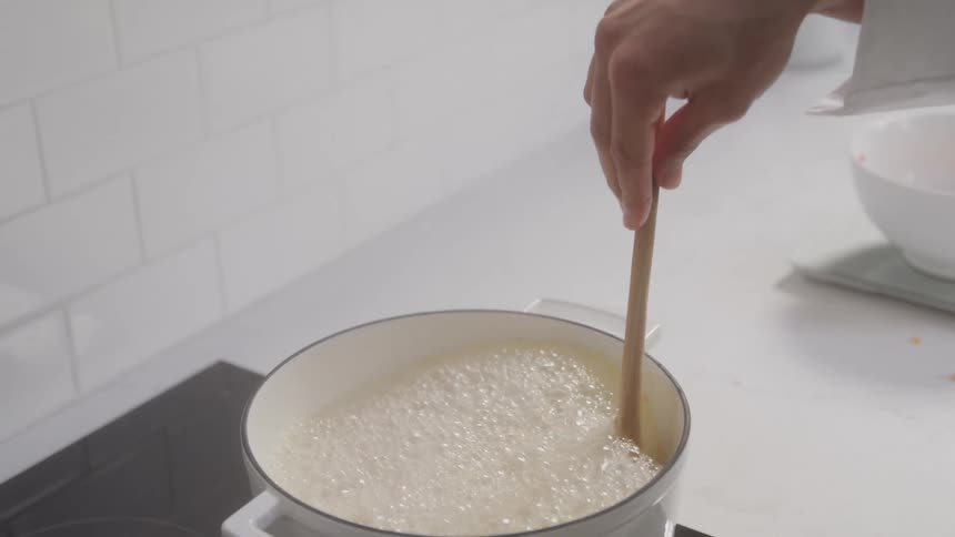 A person is stirring a bowling pot