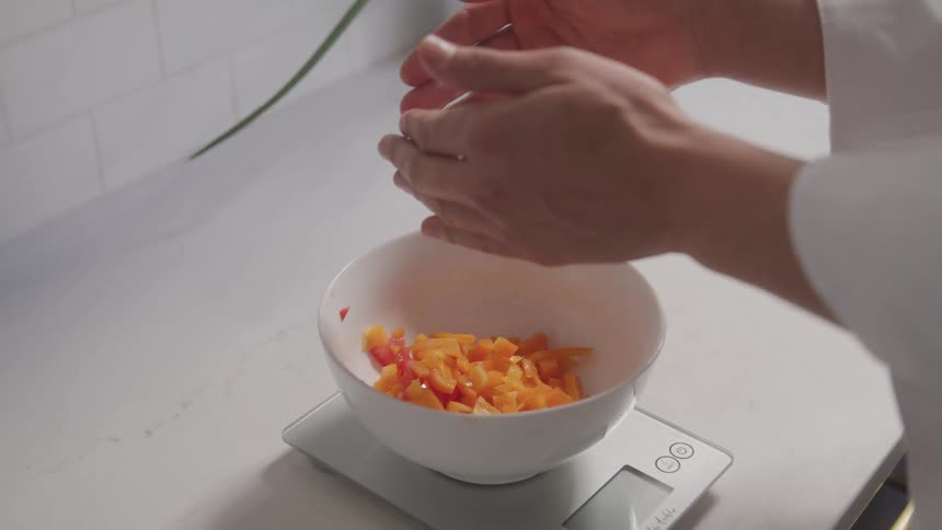 Hands pouring pieces of fruit into a bowl
