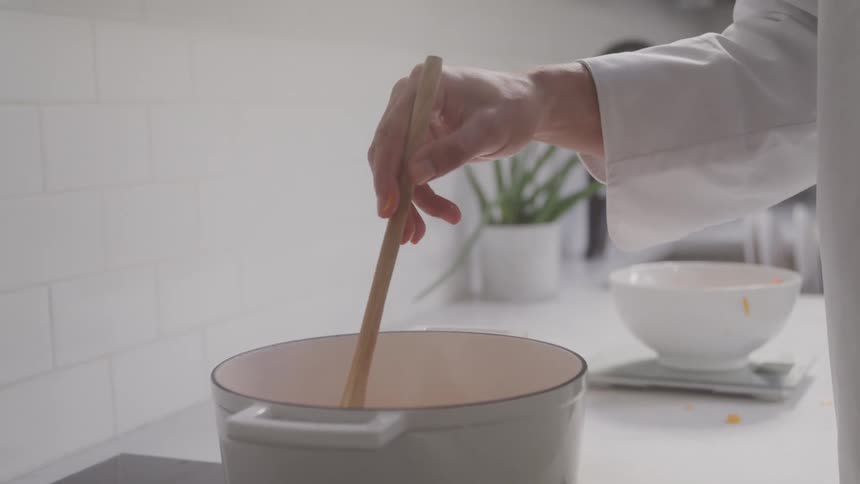 A man is stirring a pot in the kitchen