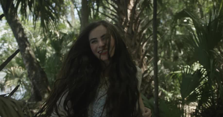 Woman smiling and running through palm tree forest
