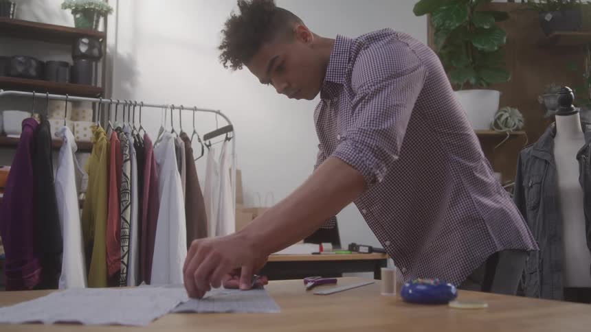 A tailor is measuring fabric on the table