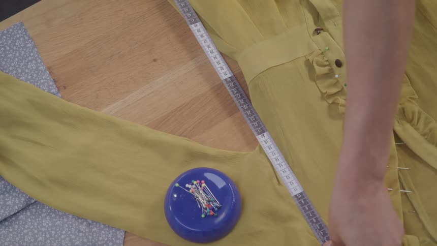 Person measuring a piece of clothing on a table